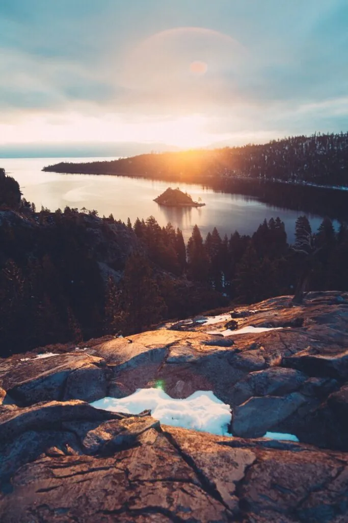 Sunset casting light on a scenic lake and island.